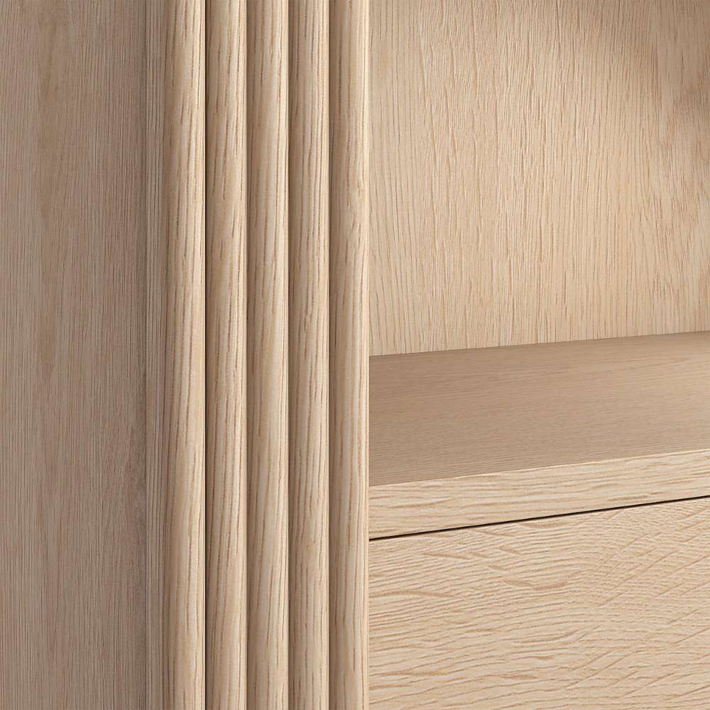 Close-up of Crate & Barrel Siena 34" Whitewash Wood 4-Shelf Storage Bookcase with Drawer highlighting the whitewash wood grain and fluted accents