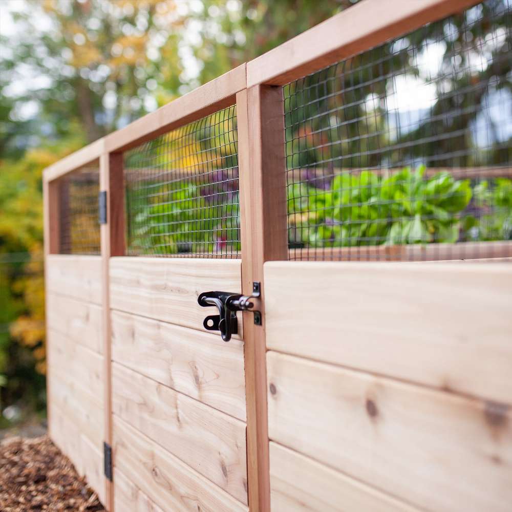 Close-up of Outdoor Living Today 8×5 Raised Garden Bed highlights its wooden frame, wire mesh panels, and black latch on the gate