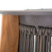 Close-up of Westminster Teak Luna Standing Lamp shows a sleek metal ring securing tightly woven dark rope around a cylindrical frame beside smooth wooden legs