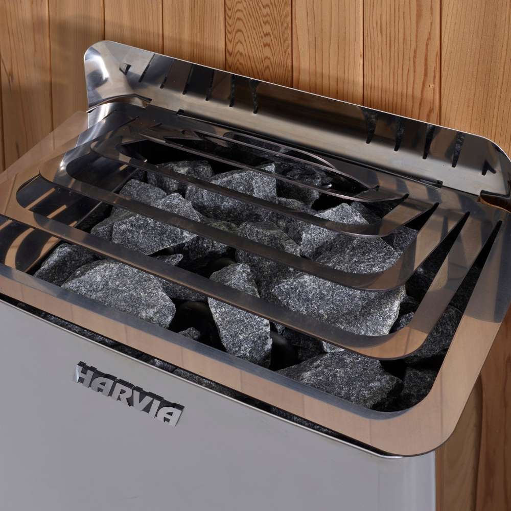Close-up of gray sauna stones under steel guard rails on top of the Harvia stove in Golden Designs Arosa 4 Person Barrel Traditional Sauna