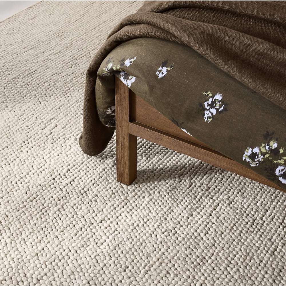 Close-up of the Crate & Barrel Keane Solid Driftwood King Bed footboard corner showing the solid wood leg and clean-lined frame