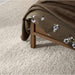Close-up of the Crate & Barrel Keane Solid Driftwood King Bed footboard corner showing the solid wood leg and clean-lined frame
