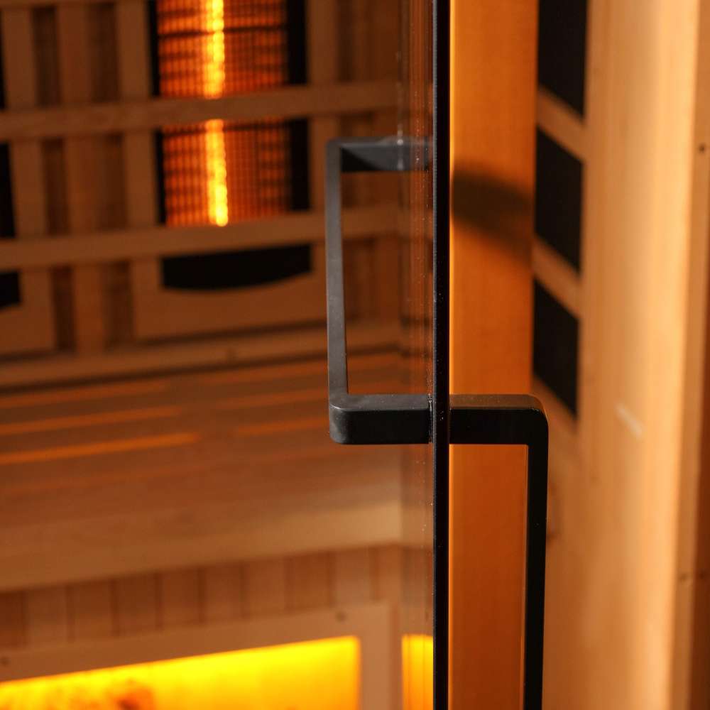 Close-up of the black finish door handle on the glass door of Golden Designs Reserve Edition 2 Person Full Spectrum Sauna with Himalayan Salt Bar, with amber light inside