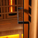 Close-up of the black finish door handle on the glass door of Golden Designs Reserve Edition 2 Person Full Spectrum Sauna with Himalayan Salt Bar, with amber light inside