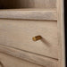 Close-up of the brass drawer knob and weathered natural wood grain on Crate & Barrel Keane 40" Weathered Natural Wood Storage Bookcase