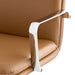 Close-up of the chrome armrest and camel faux leather seat on Crate & Barrel Smythe Camel Faux Leather Office Chair, showing the chair's sleek finish and padding