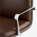 Close-up of the chrome armrest and chocolate faux leather seat on Crate & Barrel Smythe Chocolate Faux Leather Office Chair