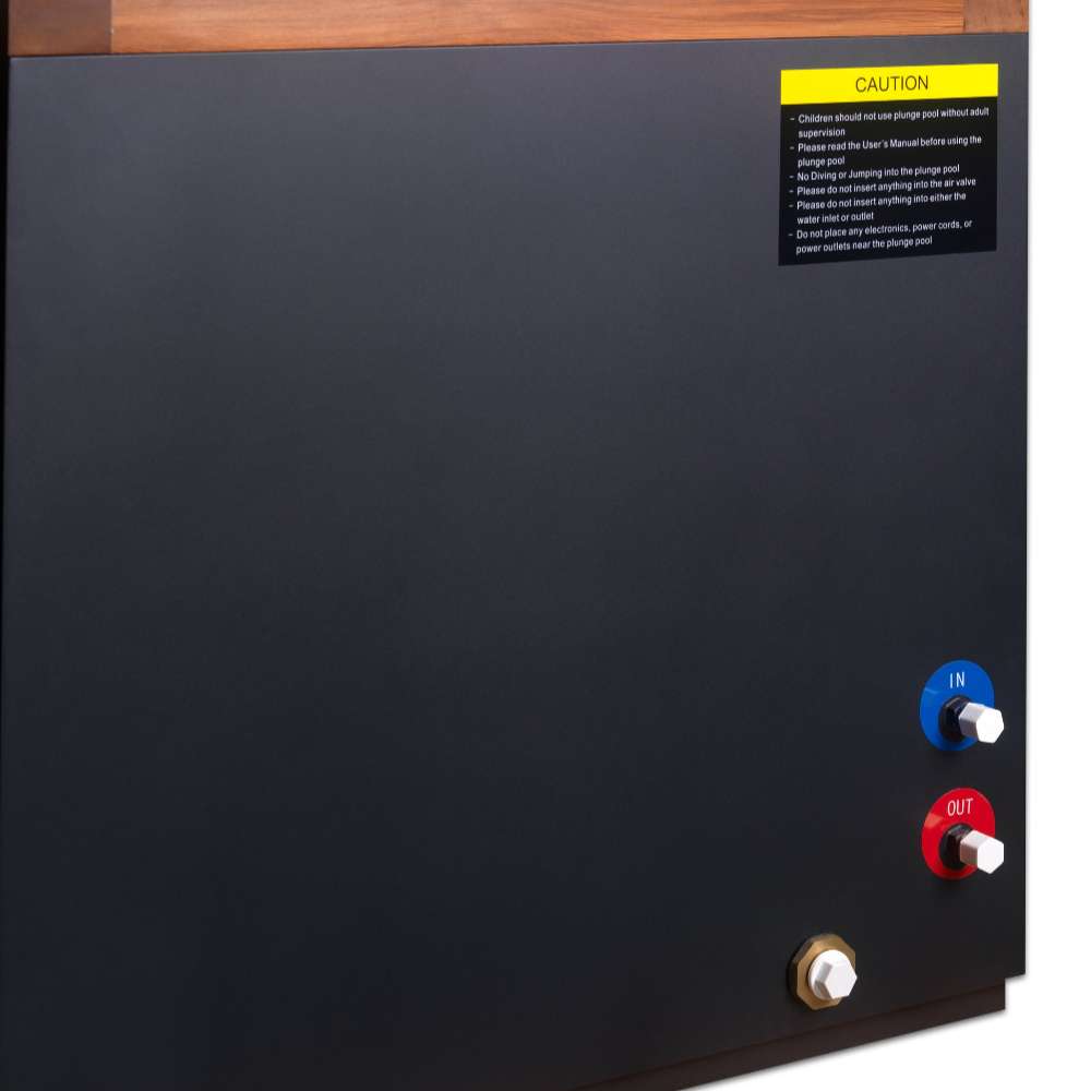 Close-up of the dark gray side panel of Golden Designs Dynamic Cold Therapy Cuboid Plastic Cold Plunge Tub showing blue and red water connection ports, a brass drain fitting and a yellow caution label
