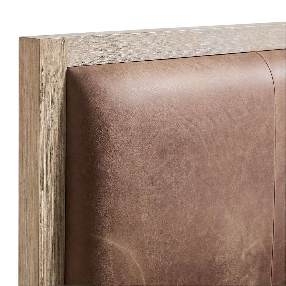Close-up of the leather upholstered headboard on Crate & Barrel Keane Weathered Natural Wood and Leather Queen Bed with a weathered natural wood frame
