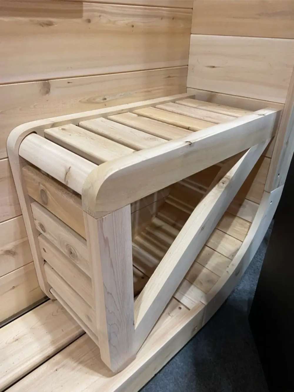 Close-up of the corner bench on the front porch of Sawmill Structures Box Sauna showcasing its slatted design and curved edge