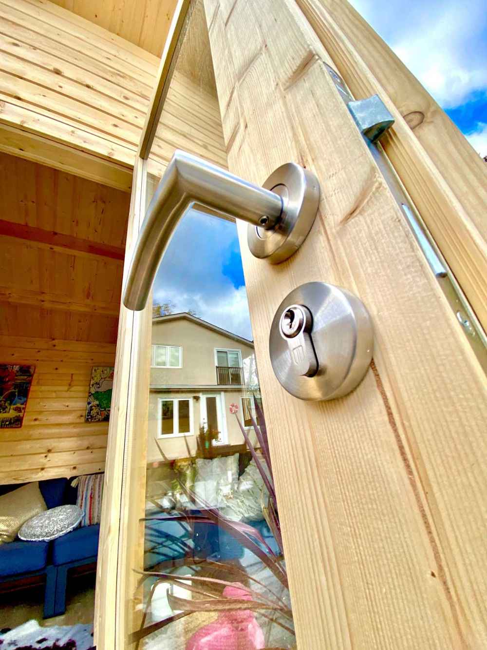 Close-up of the door handle and lock of the Sawmill Structures The Versa 107 70MM Garden Room reveals its quality metal finish and glass panel