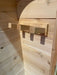 Close-up of three sturdy wooden hooks mounted on the wall inside Sawmill Structures Box Sauna