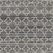 Close-up pattern shot of Couristan Fez Indoor/Outdoor Rug - Riad/Tobacco displays cream geometric shapes over a textured gray and black background