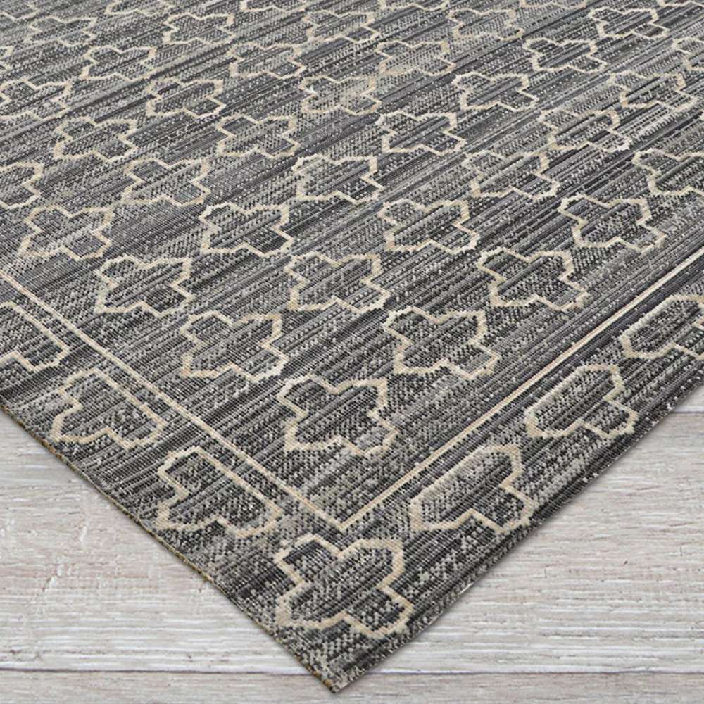 Close-up view of Couristan Fez Indoor/Outdoor Rug - Riad/Tobacco shows a textured gray background with cream geometric cross-like patterns