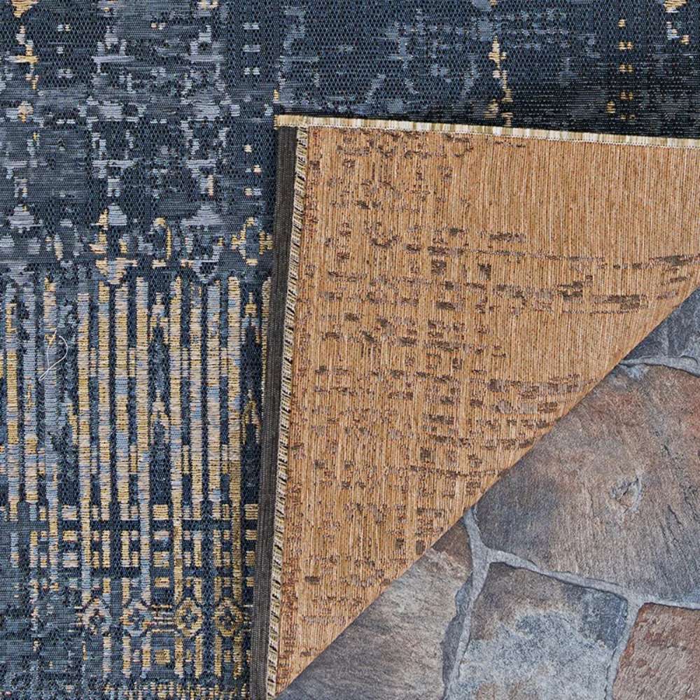 Close-up view shows Couristan Dolce Indoor/Outdoor Rug - Blue Nile/Indigo with its corner flipped to reveal the tan underside and intricate weave