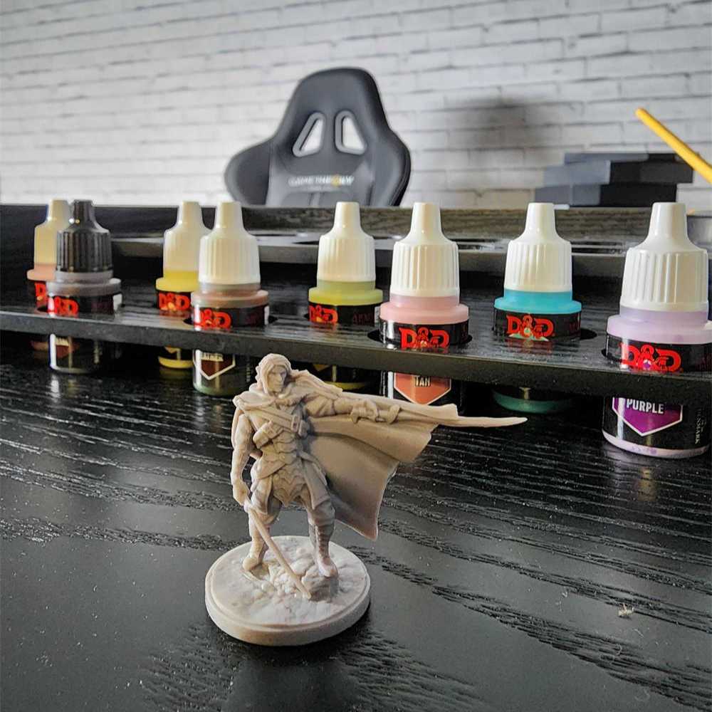 Close-up of the onyx Game Theory Tables Origins Minature Work Station with paint bottles and a mini figure