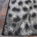 Closer view of Couristan Dolce Indoor/Outdoor Rug - Lynx/Ivory-Charcoal displays the corner lying flat on a stone patio