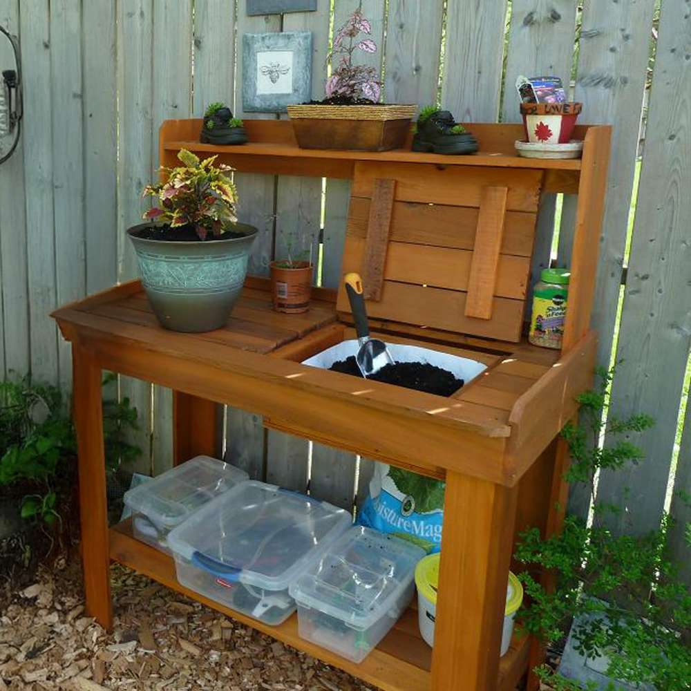Compact garden setup shows a potting bench with storage bins and soil, with Outdoor Living Today 4×2 Western Red Cedar Potting Bench at the center