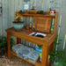 Compact garden setup shows a potting bench with storage bins and soil, with Outdoor Living Today 4×2 Western Red Cedar Potting Bench at the center