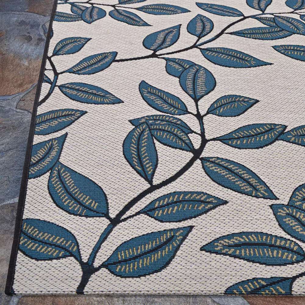 Corner-angle shot of Couristan Dolce Indoor/Outdoor Rug - Summer Ivy/Ivory-Slate Blue highlights its black-trimmed edges and sturdy weave