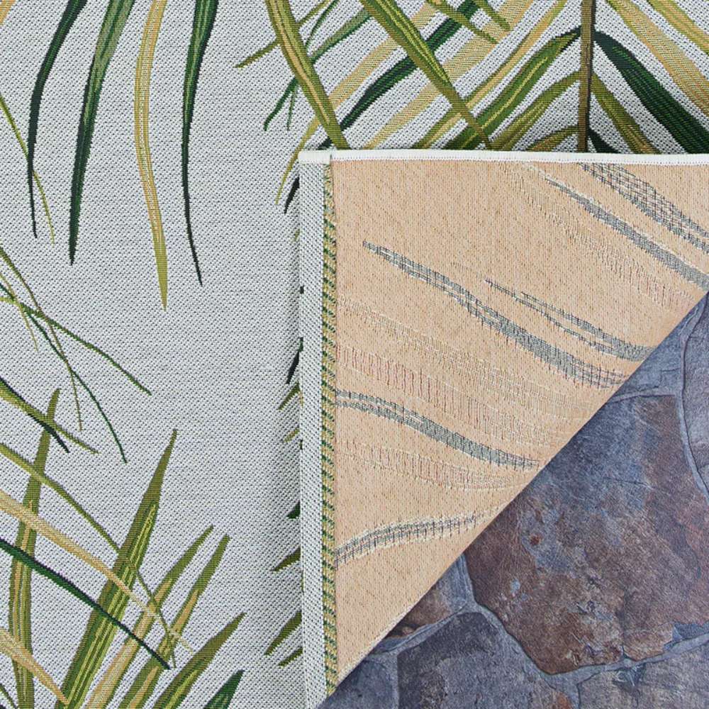 Corner of Couristan Dolce Indoor/Outdoor Rug - Bamboo Forest/Frost showing the front palm frond design and the tan-colored back texture