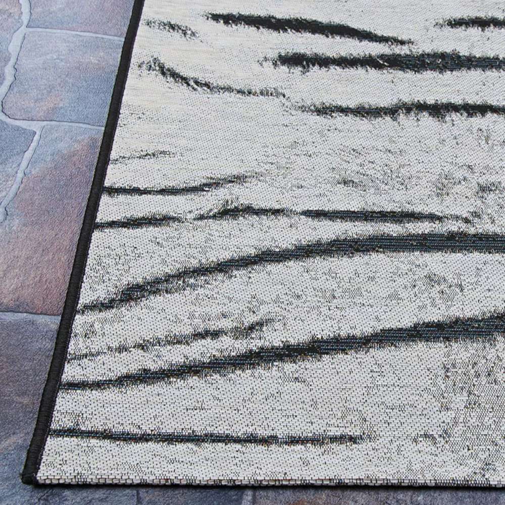 Corner of Couristan Dolce Indoor/Outdoor Rug - Bengal/Ivory placed on outdoor stone flooring