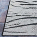 Corner of Couristan Dolce Indoor/Outdoor Rug - Bengal/Ivory placed on outdoor stone flooring