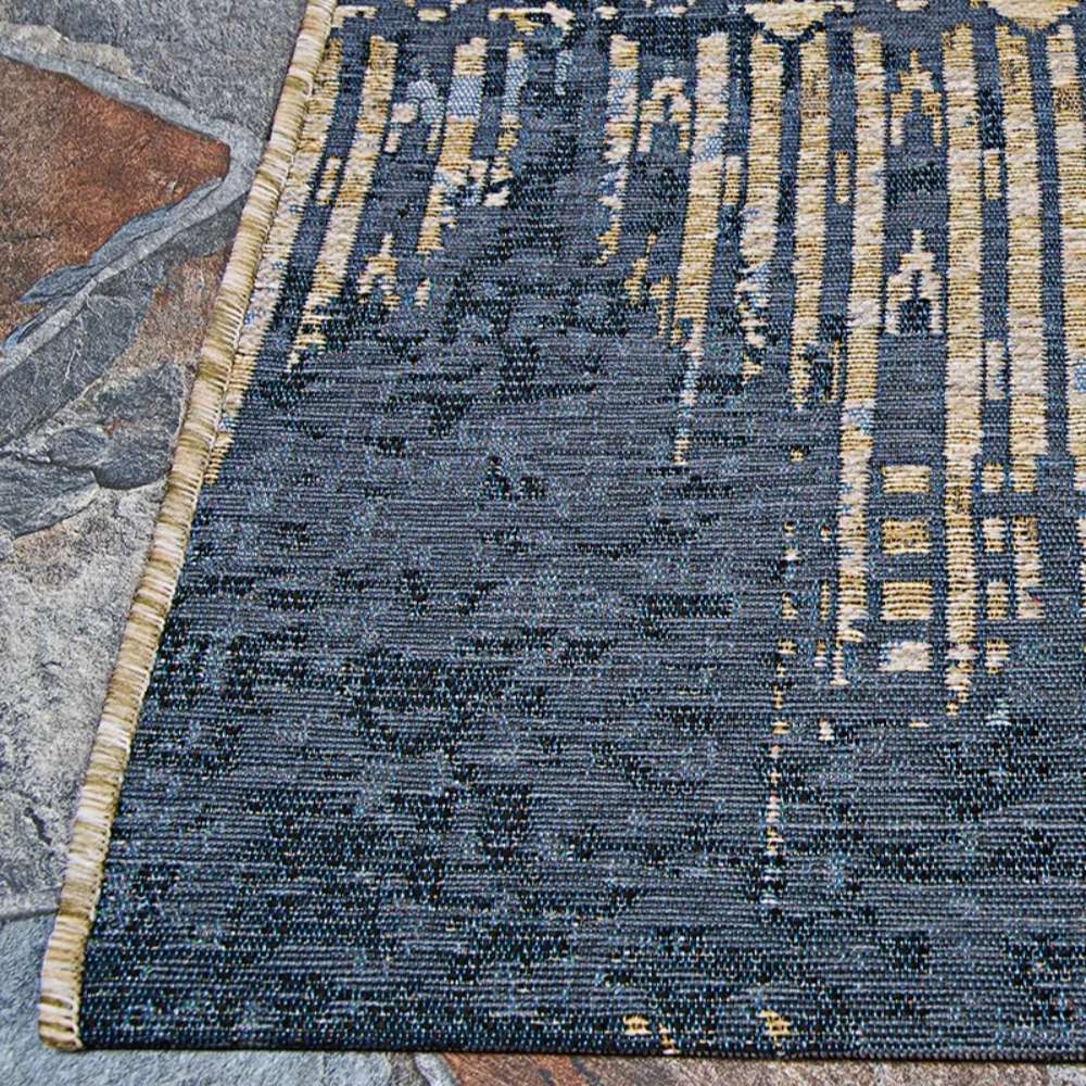 Corner of Couristan Dolce Indoor/Outdoor Rug - Blue Nile/Indigo lies neatly on a stone patio