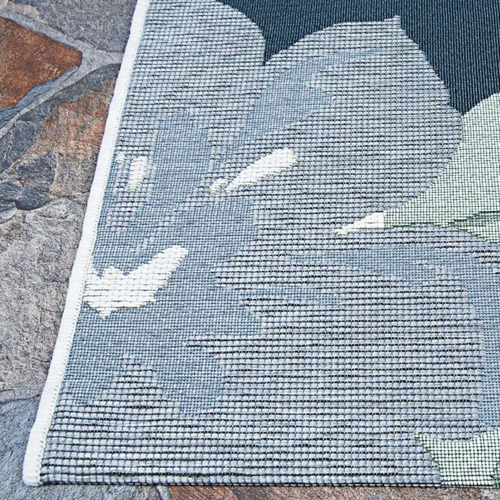 Corner of Couristan Dolce Indoor/Outdoor Rug - Novella/Grey showcases detailed woven blue and white flower petals with a light-colored stitched edge