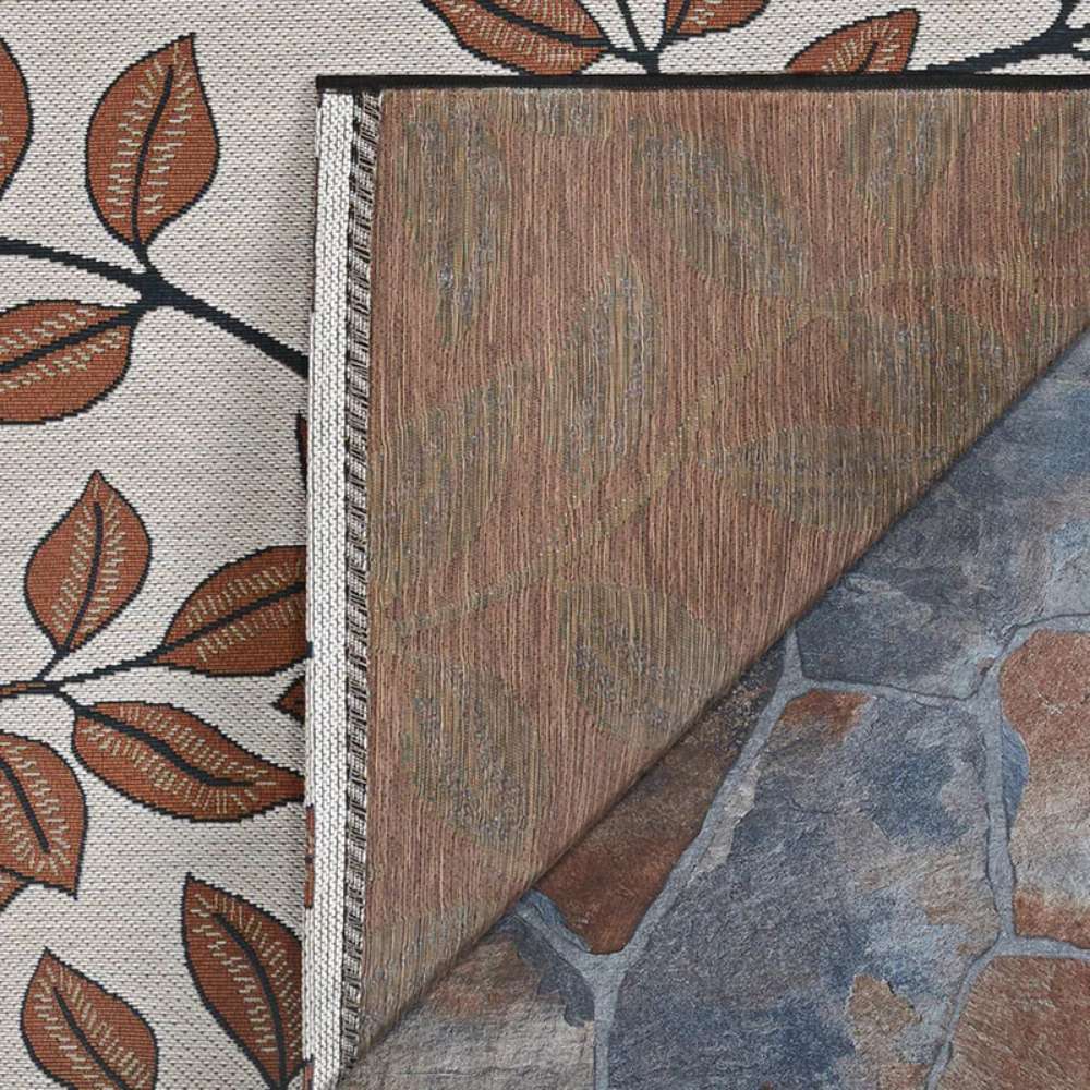Corner of Couristan Dolce Indoor/Outdoor Rug - Summer Ivy/Ivory-Terra-Cotta is flipped to show its brown textured underside
