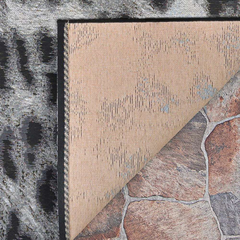 Corner of a Couristan Dolce Indoor/Outdoor Rug - Lynx/Ivory-Charcoal shows the front with a black-and-white pattern and the back folded over revealing the underside