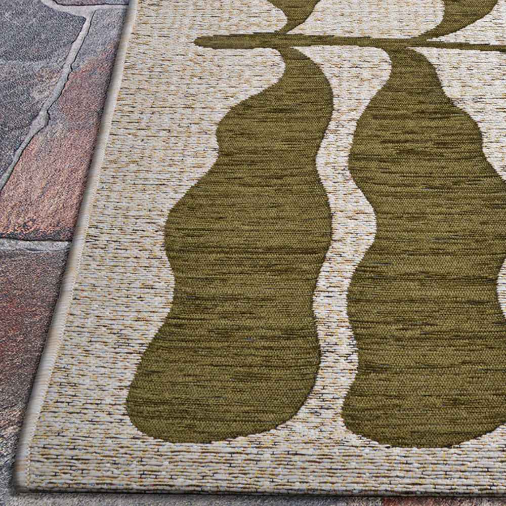 Corner of the Couristan Castille Indoor/Outdoor Rug - Fiore/Tea Leaf resting on a stone floor