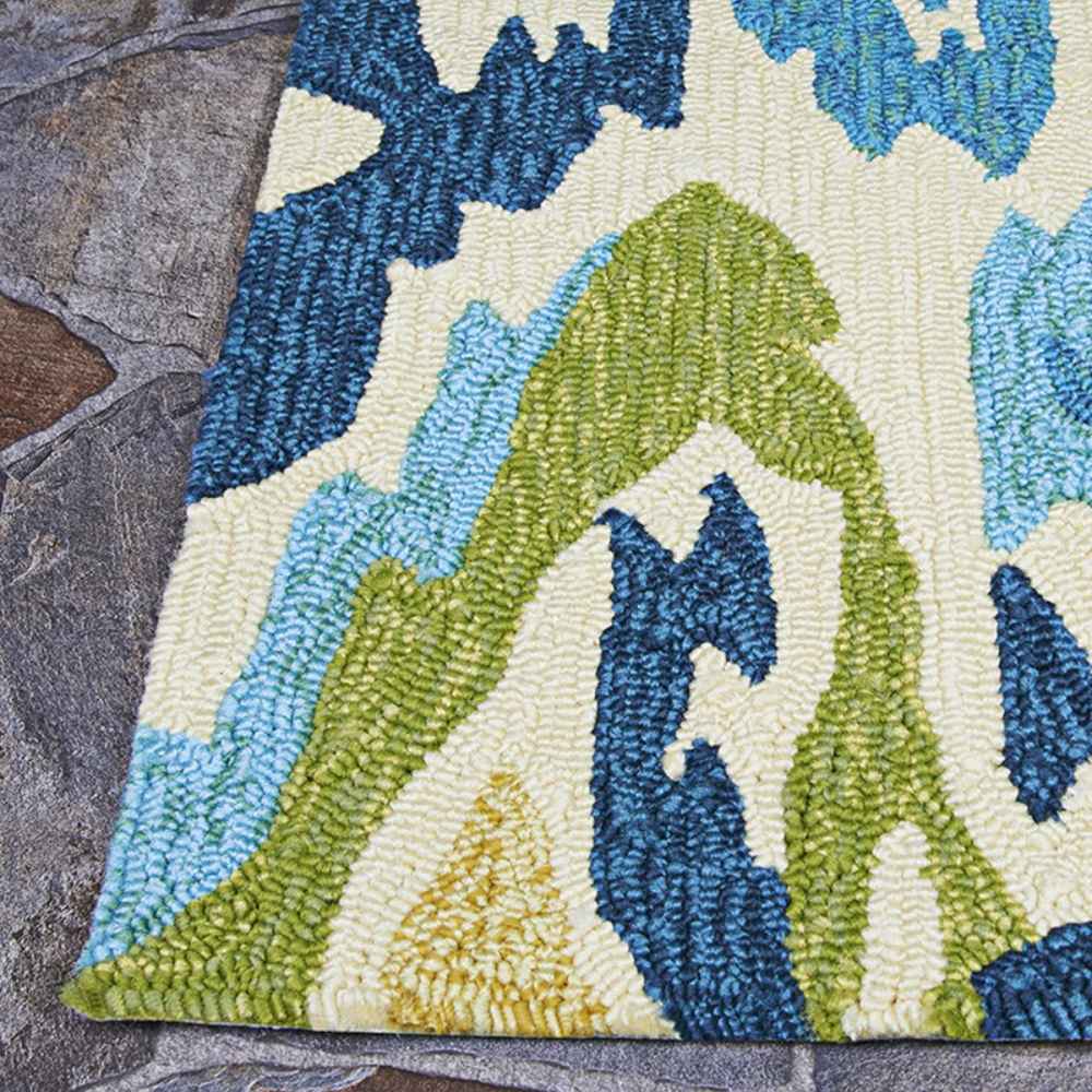 Corner of the Couristan Covington Indoor/Outdoor Rug - Delfina/Azure-Lemon highlights its neatly finished edge and bold, colorful design against stone flooring
