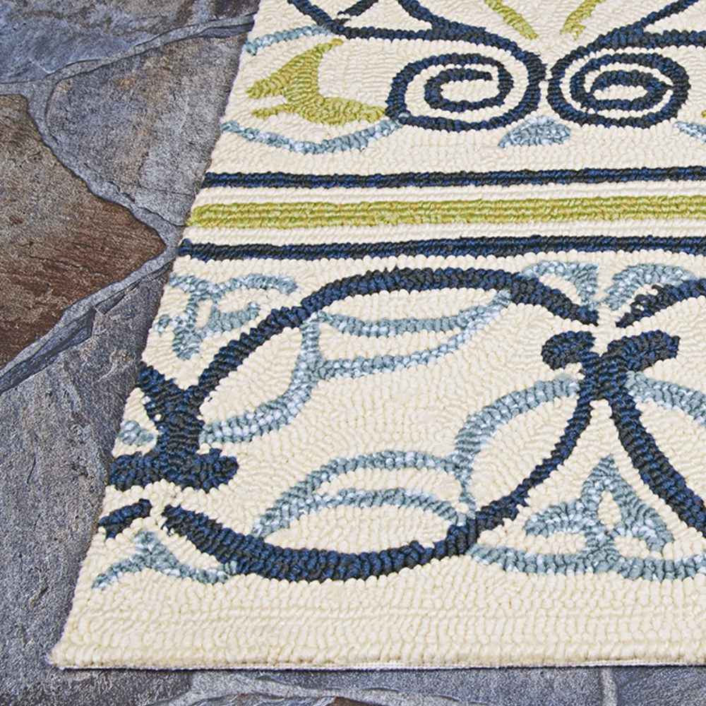 Corner of the Couristan Covington Indoor/Outdoor Rug - Pegasus/Ivory-Navy-Lime rests on slate tiles