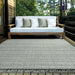 Couristan Ascot Indoor/Outdoor Rug - Windowpane/Celedon is laid out on a patio beneath a wooden sofa, creating a calm, cozy outdoor space