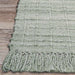 Couristan Ascot Indoor/Outdoor Rug - Windowpane/Celedon sits on a wood floor with detailed fringe and visible grid-like stitching