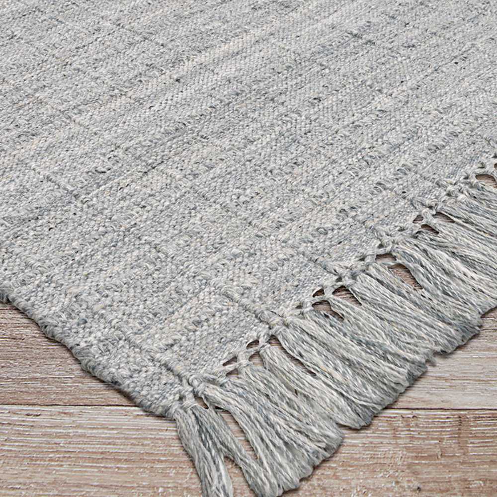 Couristan Ascot Indoor/Outdoor Rug - Windowpane/Grey is pictured from an angle, showcasing its uniform grid pattern and neatly finished fringe