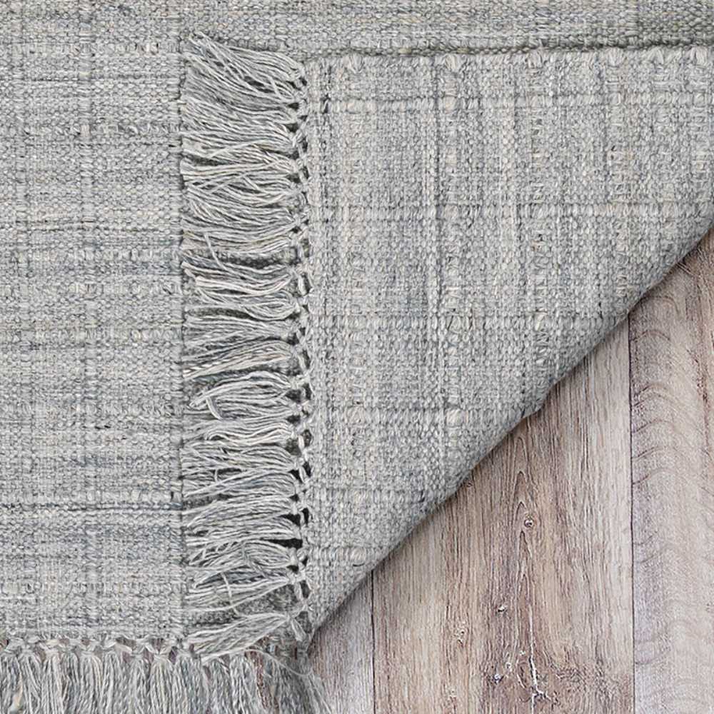 Couristan Ascot Indoor/Outdoor Rug - Windowpane/Grey is shown close-up with its textured weave and fringe detail clearly visible on wooden flooring