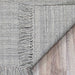 Couristan Ascot Indoor/Outdoor Rug - Windowpane/Grey is shown close-up with its textured weave and fringe detail clearly visible on wooden flooring