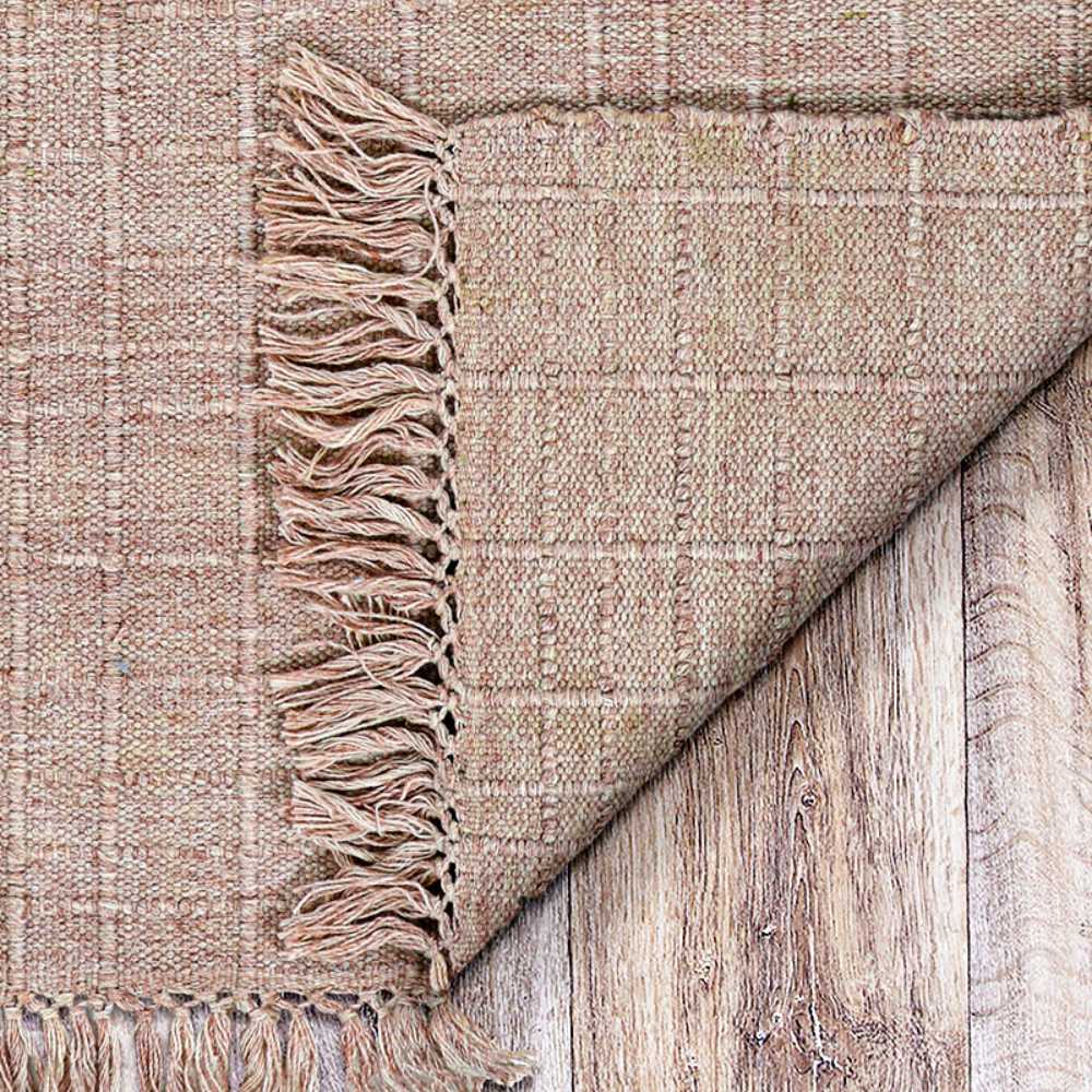 Couristan Ascot Indoor/Outdoor Rug - Windowpane/Rose is partially flipped on wood flooring, revealing its tight weave and rose-ivory blend