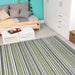 Couristan Cape Indoor/Outdoor Rug - Brockton/Hunter Green-Brown lies on a light wood floor in a cozy bedroom with a daybed and white cabinet