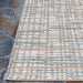 Couristan Cape Indoor/Outdoor Rug - Falmouth/Ivory-Coral is shown outdoors on a stone patio