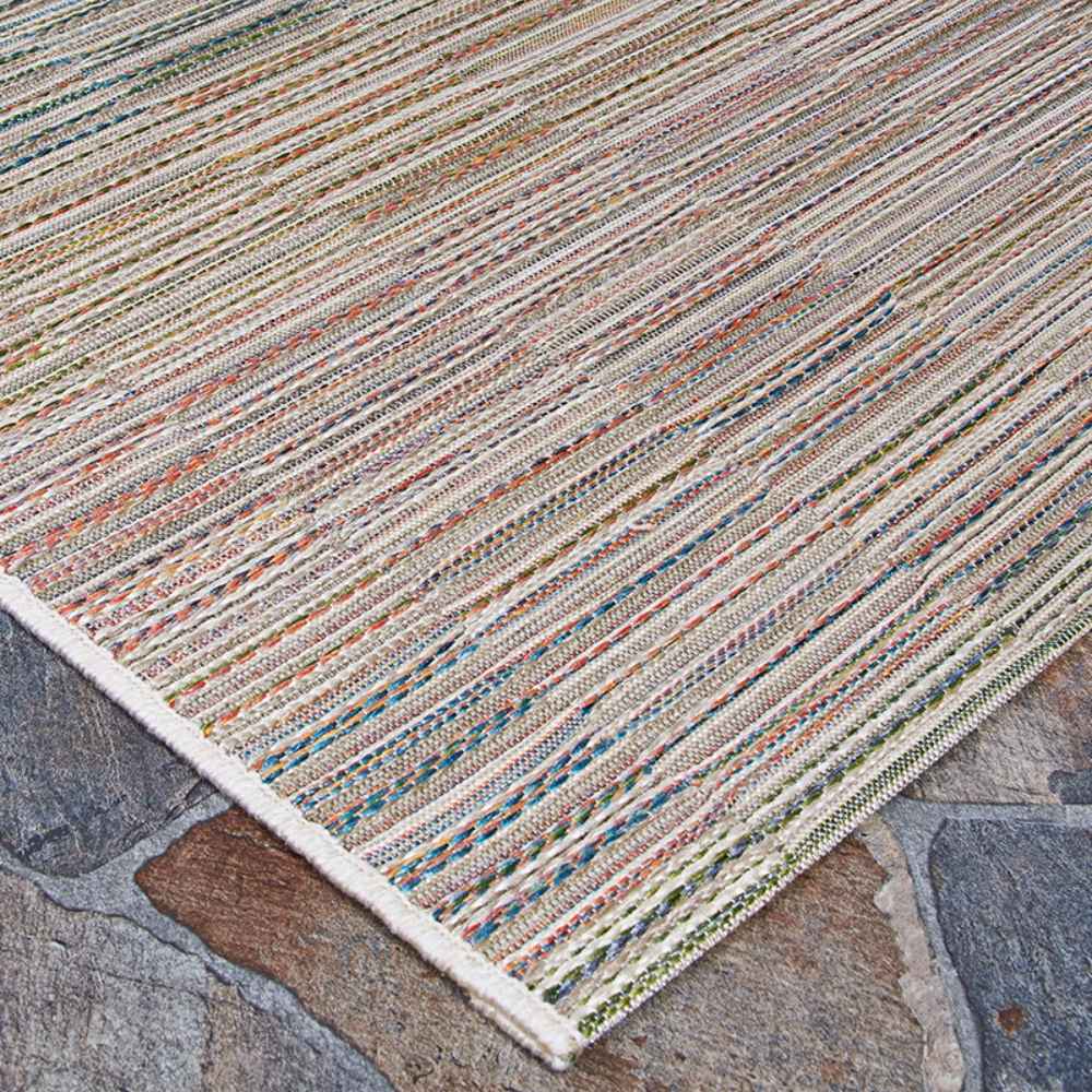 Couristan Cape Indoor/Outdoor Rug - Fayston/Multi is captured at an angle to show its woven multicolor detail against a rustic stone surface