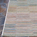 Couristan Cape Indoor/Outdoor Rug - Fayston/Multi lies flat on a stone patio, showcasing its colorful striped design up close