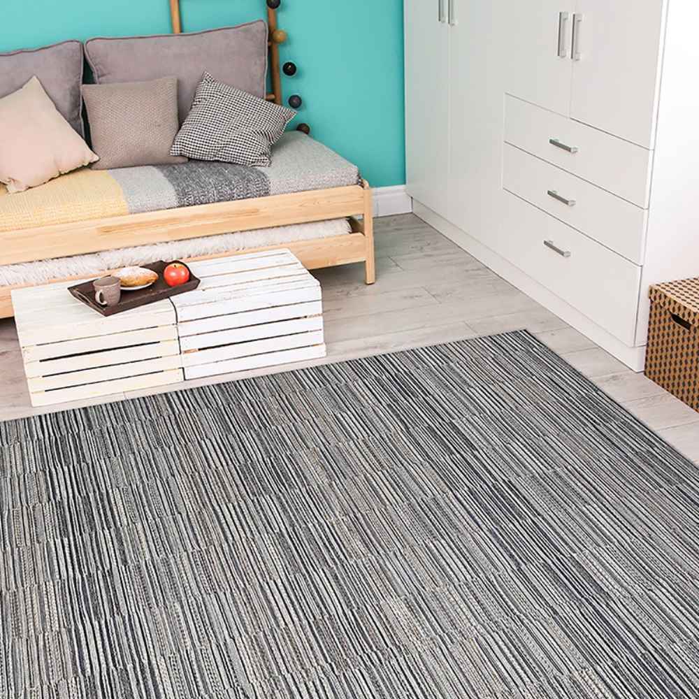 Couristan Cape Indoor/Outdoor Rug - Fayston/Silver-Charcoal is placed in a cozy, modern room with light wood flooring, a daybed, and bright teal walls