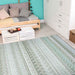 Couristan Cape Indoor/Outdoor Rug - Gables/Palm is laid out in a cozy, modern room with light wood furniture and a teal wall