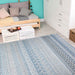 Couristan Cape Indoor/Outdoor Rug - Gables/Surf is laid out in a bright, modern room with a wooden daybed, white furniture, and turquoise walls