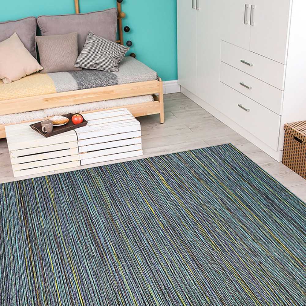 Couristan Cape Indoor/Outdoor Rug - Hinsdale/Teal-Cobalt is laid out in a bright room with a wooden daybed, white furniture, and turquoise wall