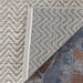 Couristan Cape Indoor/Outdoor Rug - Marion/Light Brown-Ivory is flipped at the corner, revealing its durable underside on a stone patio