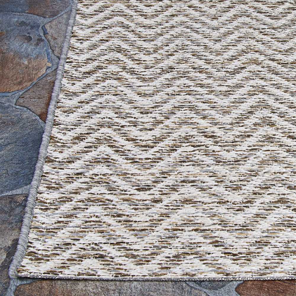 Couristan Cape Indoor/Outdoor Rug - Marion/Light Brown-Ivory is shown on a stone floor with a neat border and repeating chevron design